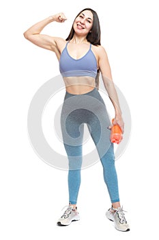 A beautiful, athletic, slender and cheerful woman demonstrates a muscular biceps arm and holds a bottle of water