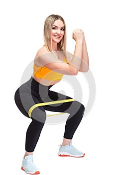 A beautiful, athletic, slim, smiling and cheerful woman in an orange top and black sweatpants performs squats with a