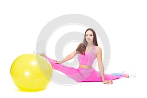 A beautiful, athletic, slim, smiling and cheerful woman in a pink tracksuit demonstrates stretching. Sits on a twine