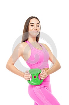 A beautiful, athletic, slim, smiling and cheerful woman in a pink tracksuit holds a green barbell pancake in her hands