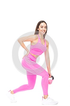 A beautiful, athletic, slim, smiling and cheerful woman in a pink tracksuit performs exercises with a pink kettlebell