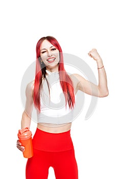 A beautiful, athletic, slim, smiling and cheerful woman in a white top and red sweatpants demonstrates her biceps and