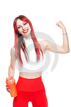 A beautiful, athletic, slim, smiling and cheerful woman in a white top and red sweatpants demonstrates her biceps and