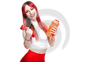 A beautiful, athletic, slim, smiling and cheerful woman in a white top and red sweatpants holds a red dumbbell and a
