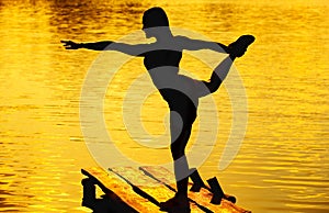 Beautiful, athletic woman doing yoga on the old, wooden bridge.