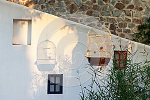 Beautiful atmospheric Mediterranean landscape. Golden cage with goldfinch casts shadow on wall, setting summer sun. Courtyard of