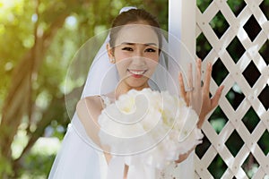 Beautiful Attractive Asian Bride Woman wearing white wedding dress and holding bouquet smile