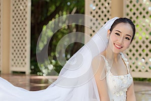Beautiful Attractive Asian Bride Woman wearing white wedding dress and holding bouquet smile