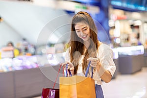 Beautiful Attractive Asian woman open shopping bags after shopping smile and enjoy with it in shopping mall