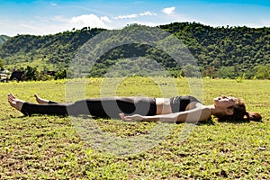 Beautiful Attractive Asian woman practice yoga Dead Body pose or Savasana pose lying on green grass for yoga Meditation