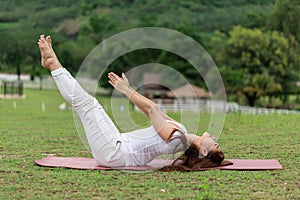 Beautiful Attractive Asian woman practice yoga Dead Body pose or Uttana Padasana pose lying on yoga mat with green grass for yoga photo