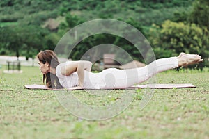 Beautiful Attractive Asian woman practice yoga Locust or Shalabhasana pose with yoga meditation relax and refresh health on Meadow