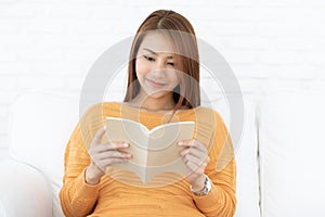 Beautiful Attractive Asian woman sitting on sofa in living room reading book