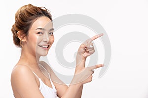 Beautiful Attractive Asian young women smile and pointing to copy space for display Cosmetics product feeling happiness