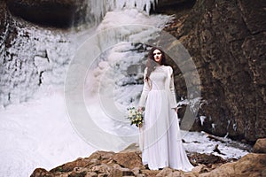 Beautiful bride with a wedding bouquet of flowers on a background with a glacier and mountains