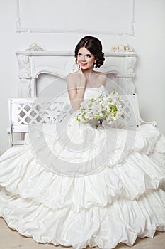 Beautiful attractive bride in wedding luxurious dress with voluminous skirt posing in modern interior