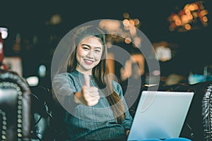 Beautiful Attractive Business Asian woman working with laptop looking in monitor smile and showing Thumbs up