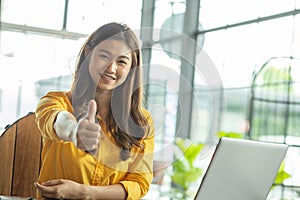 Beautiful Attractive Business Asian woman working with laptop looking in monitor smile and showing Thumbs up have positive emotion