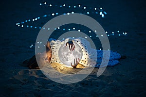 Beautiful attractive girl on a night beach with sand and stars hugs the moon, Artistic Photography