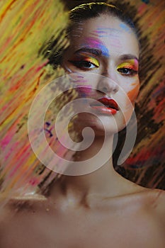 Beautiful attractive woman in color paint splash behind the painted color glass photo