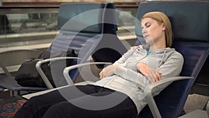 Beautiful attractive woman sleeping in airport terminal. Long distance connected flights jet-lag.