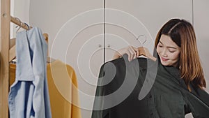 Beautiful attractive young Asian woman choosing her fashion outfit clothes in closet at home or store. Girl think what to wear