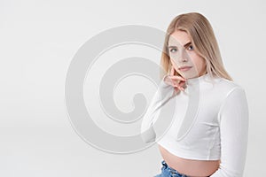 Beautiful attractive young blonde woman in white clothes, on a white  background, looking at the camera, studio portrait,