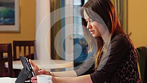 Beautiful attractive young woman reads news in tablet PC office