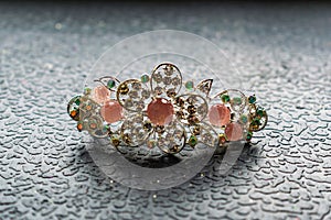 Beautiful automatic barrette with shiny stones and pink beads on dark textured background. Gold hairpins with white rhinestones.