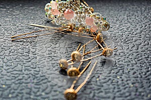 Beautiful automatic barrette with shiny stones and pink beads on dark textured background. Gold hairpins with white rhinestones.