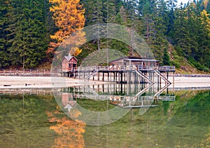 Beautiful autumn alpine landscape, old wooden dock house with pier on Braies lake, Dolomites, Italy