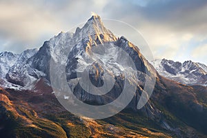 Beautiful autumn alpine landscape with snow-capped mountains and colorful forest at sunrise