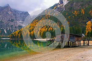 Beautiful autumn alpine landscape, spectacular old wooden dock house with pier on Braies lake, Dolomites, Italy