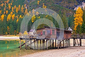 Beautiful autumn alpine landscape, spectacular old wooden dock house with pier on Braies lake, Dolomites, Italy