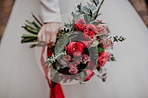 Beautiful autumn bouquet with red flowers and succulents in the bride`s hand