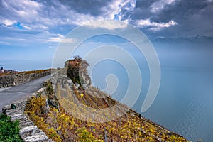 Beautiful autumn colors on the terraces of the Lavaux vineyards in Switzerland and foggy, dark threatening clouds over Lake Geneva