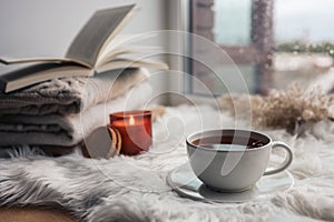 Beautiful autumn composition with burning candle and cup of tea on window sill