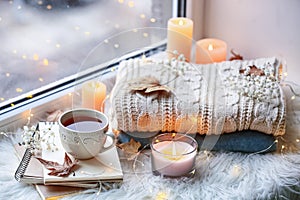 Beautiful autumn composition with burning candles and cup of tea on window sill