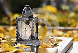 Beautiful autumn concept to the cemetery and Halloween. Candle in a lantern on the grave. Background for Halloween.