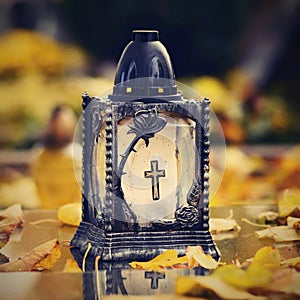 Beautiful autumn concept to the cemetery and Halloween. Candle in a lantern on the grave. Background for Halloween.