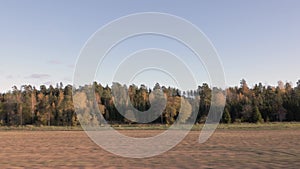 Beautiful autumn day and the view from the car. Gorgeous landscape with fields, forest trees and blue sky with white clouds.