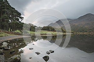 Beautiful Autumn Fall landscape image of Crummock Water at sunrise in Lake District England