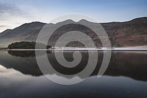 Beautiful Autumn Fall landscape image of Crummock Water at sunrise in Lake District England