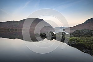 Beautiful Autumn Fall landscape image of Crummock Water at sunrise in Lake District England