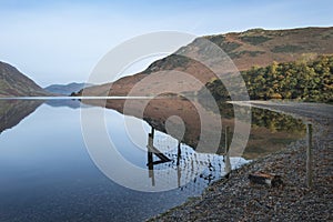 Beautiful Autumn Fall landscape image of Crummock Water at sunrise in Lake District England
