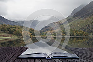 Beautiful Autumn Fall landscape image of Crummock Water at sunrise in Lake District England coming out of pages of book