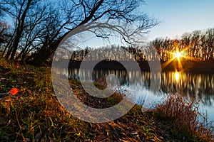 Beautiful autumn landscape in the forest, bright sunny day turns to sunset, sunlight on fallen leaves of trees, river bank and