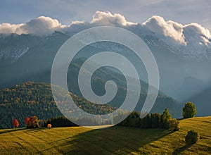 Beautiful autumn landscape in the mountains. Clouds illuminated by the morning sun floating low over the valley.