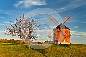 Beautiful autumn landscape with old windmill at sunset and beautiful blue sky with clouds. Colorful nature background on autumn