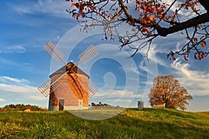 Beautiful autumn landscape with old windmill at sunset and beautiful blue sky with clouds. Colorful nature background on autumn